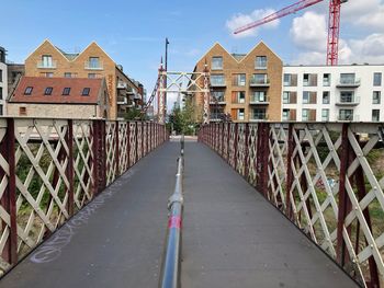 Bridge amidst buildings in city against sky