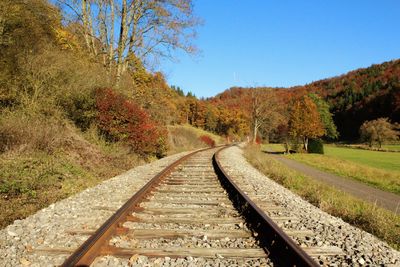 Railroad track amidst trees against clear sky