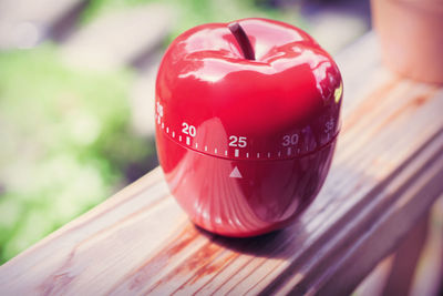 Close-up of red artificial apple on wooden railing