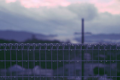 Close-up of barbed wire fence against sky