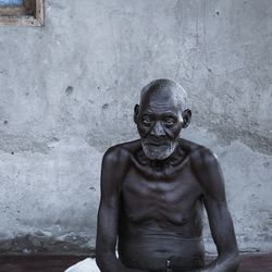 Portrait of shirtless man sitting outdoors