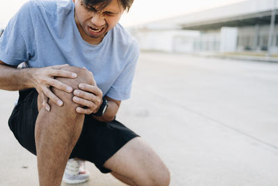 Midsection of man holding hands while sitting outdoors
