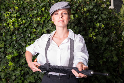 Portrait of woman wearing suspenders standing at backyard