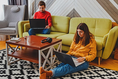 Couple working at home on their laptops in cozy stylish living room. modern lifestyle, remote work