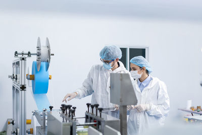 Staff and workers at the mask operation of the machines. a mask is being produced on machine.