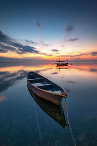 Boat moored on beach against sky during sunset