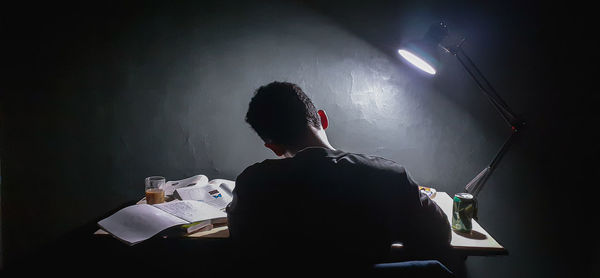 Rear view of man playing music against wall