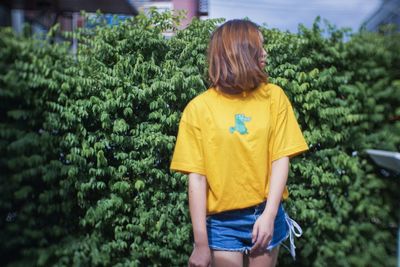 Rear view of woman standing against yellow plants