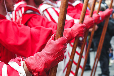 Midsection of people holding sticks