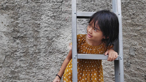 Portrait of young woman standing against wall