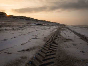 Sand dunes at beach against sky