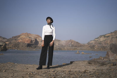 Full length of woman looking away while standing against sea