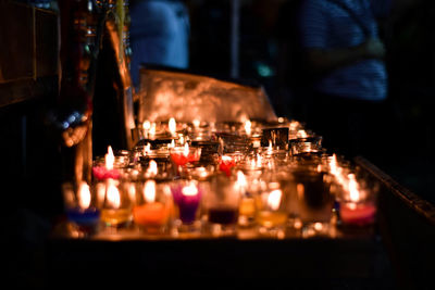 Close-up of illuminated candles on glass at night