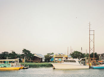 Boats sailing in river against clear sky