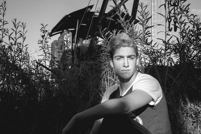 Portrait of young man sitting against plants