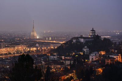 Illuminated buildings in city against sky