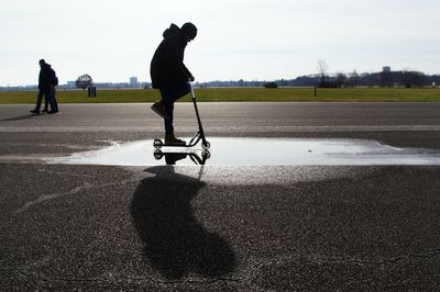 Side view of man riding scooter on road