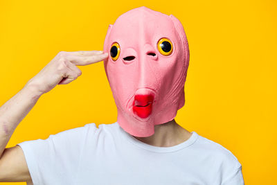 Portrait of woman wearing mask against yellow background