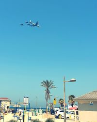 Low angle view of airplane flying against clear blue sky