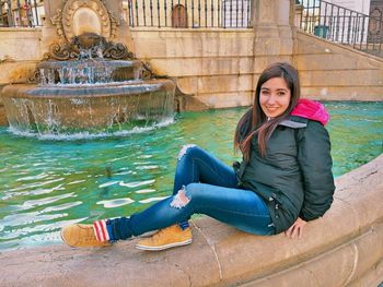 Portrait of smiling woman sitting by fountain