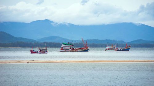 Fishing boats in sea against sky