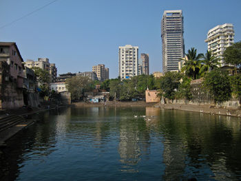 Canal by buildings against sky in city