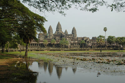 View of temple by lake against sky