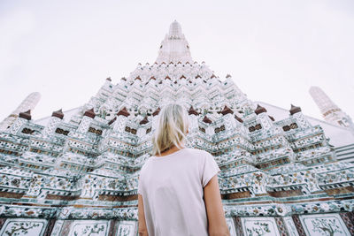 Rear view of woman standing outside building against sky