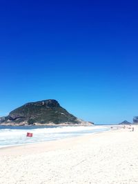 Scenic view of beach against clear blue sky
