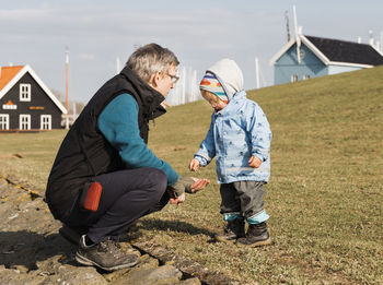 Grandfather with granddaughter wearing warm clothing on grassy field