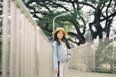 Portrait of smiling young woman standing against trees