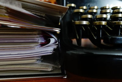 Close-up of stacked papers and typewriter on table