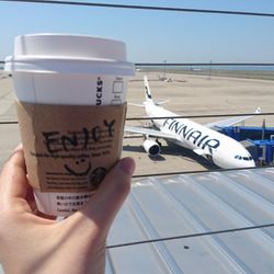 Close-up of hand holding coffee cup against sky