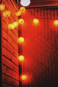 Low angle view of illuminated light bulbs hanging at night