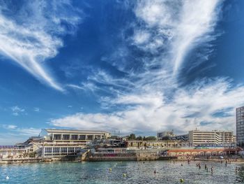 Buildings by sea against blue sky