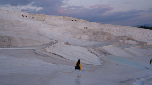 Rear view of woman walking on snow covered mountain during sunset