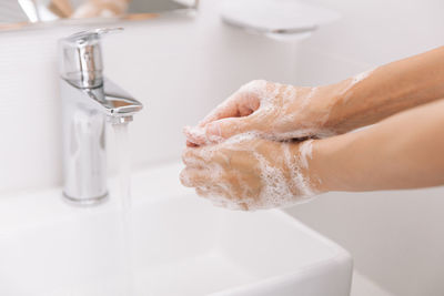 Cropped hand washing hands in sink