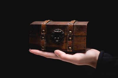 Close-up of hand holding box against black background