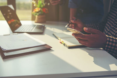 Midsection of person using mobile phone on table