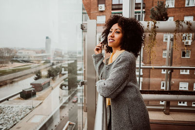 Side view of woman standing by railing in city