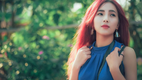 Portrait of beautiful young woman standing against blurred background