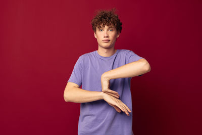 Portrait of young man gesturing against red background