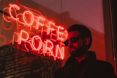 Man wearing sunglasses while standing against illuminated text