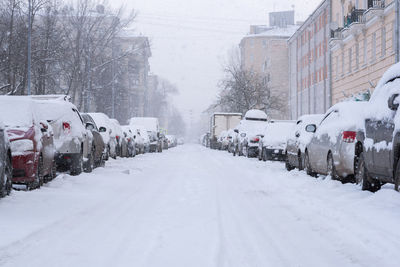 Snow covered street amidst buildings in city