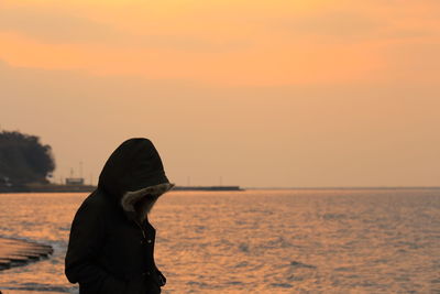 Close-up of person standing by sea against sky