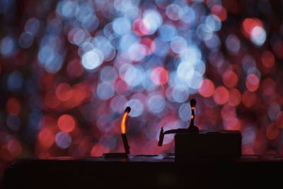 Close-up of silhouette burning matchsticks on table at night