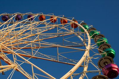 Low angle view of ferris wheel against clear blue sky