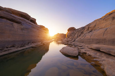 Rocks on shore against sky during sunset