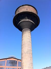 Low angle view of old industrial water tower against clear blue sky