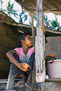 Girl looking away while sitting on wood